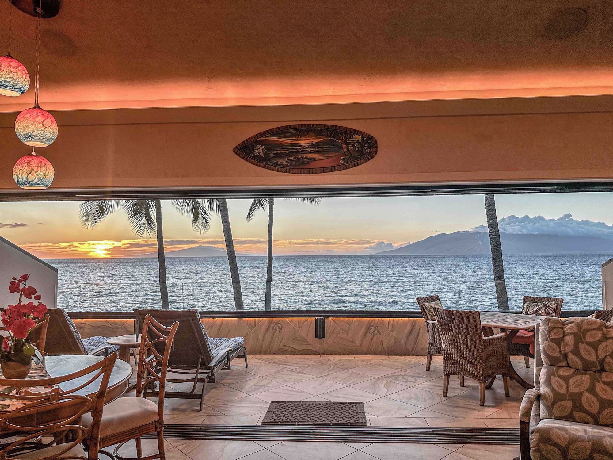 Sunset over the ocean and West Maui, seen through the open slider wall of the condo's dining room